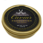 A golden tin can of American paddlefish caviar labeled 'Caviar Paddlefish Malossol' with a brand. View from side