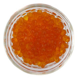 A glass jar filled with pink salmon roe caviar.
