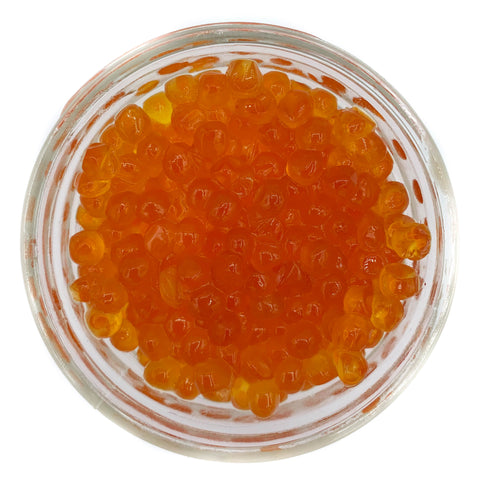 A glass jar filled with pink salmon roe caviar.